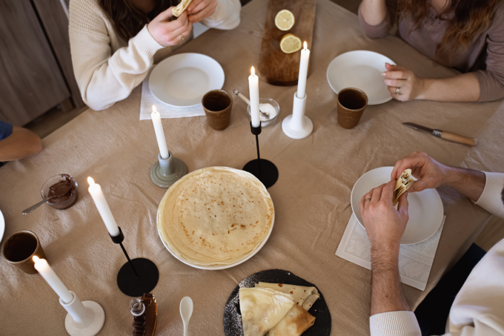 Une famille réuni autour d'une table pour partager des crêpes et célébrer la Chandeleur ensemble.