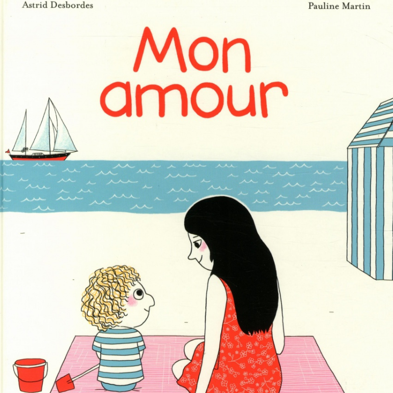 Couverture du livre "Mon Amour" Une maman et son fils assis face à la mer sur une serviette de plage avec un bateau sur l'eau et un seau et une pelle à côté du petit garçon.