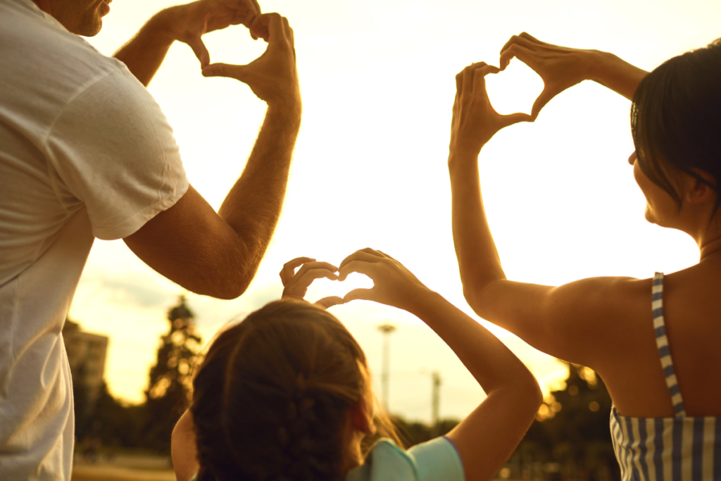 Une famille vu de dos qui forment des cœurs avec leurs mains, ce qui reflète la connexion entre le lien parents enfants.