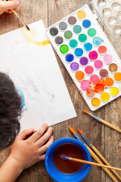 Un enfant entrain de faire de la peinture à l'eau.