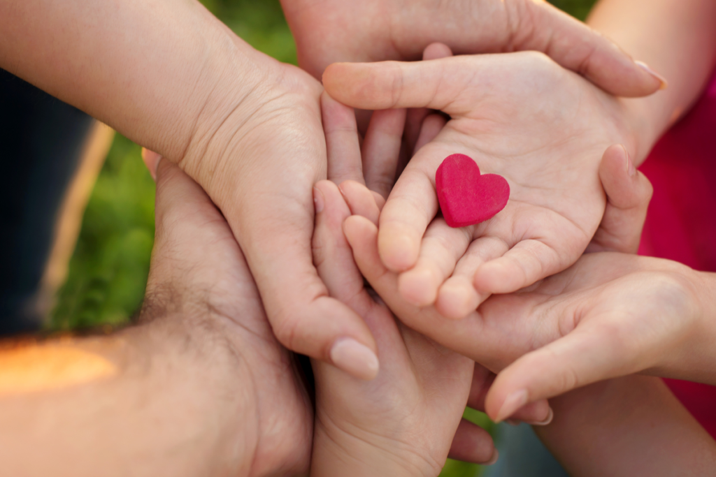 Les mains d'une même famille superposés et sur la dernière main un cœur posé pour représenter l'amour familiale.