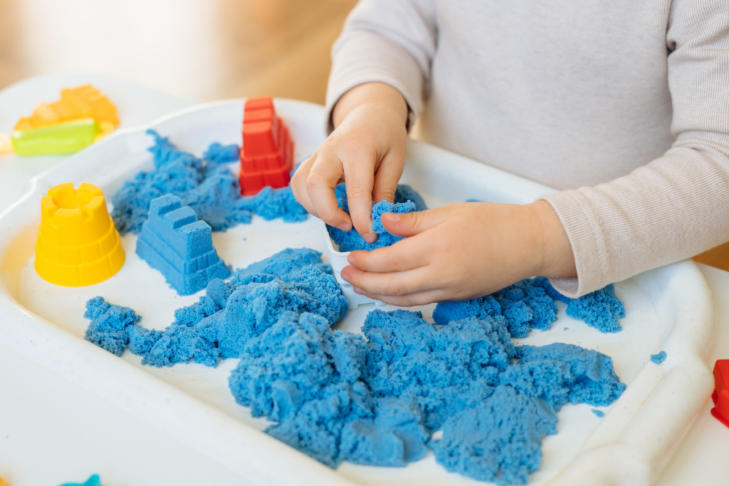 Un enfant qui joue avec du sable magique bleu pour une activité ludique, sensorielle.