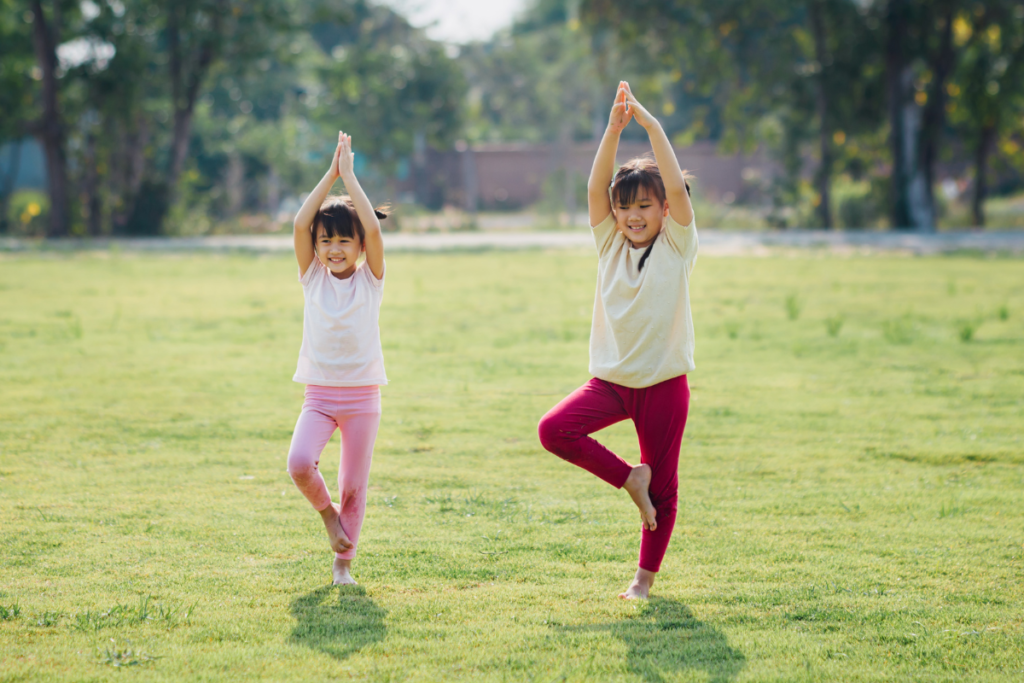 Deux enfants entrain de pratiquer une séance de yoga en pleine nature.